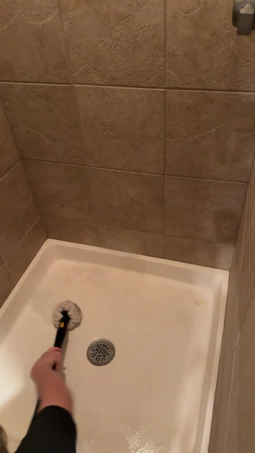 Tiled tub surround and shower head scrubbed and steam cleaned