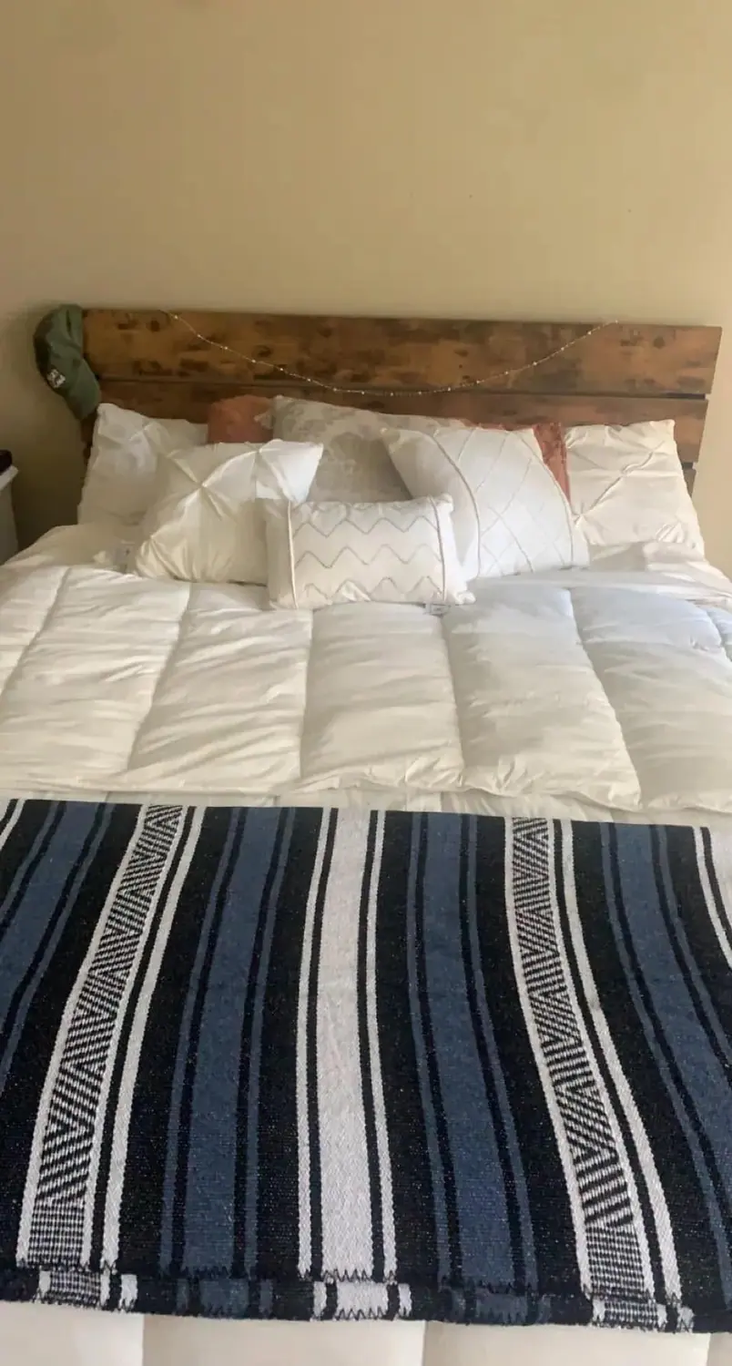 Bed remade with fresh white linens after a residential cleaning visit
