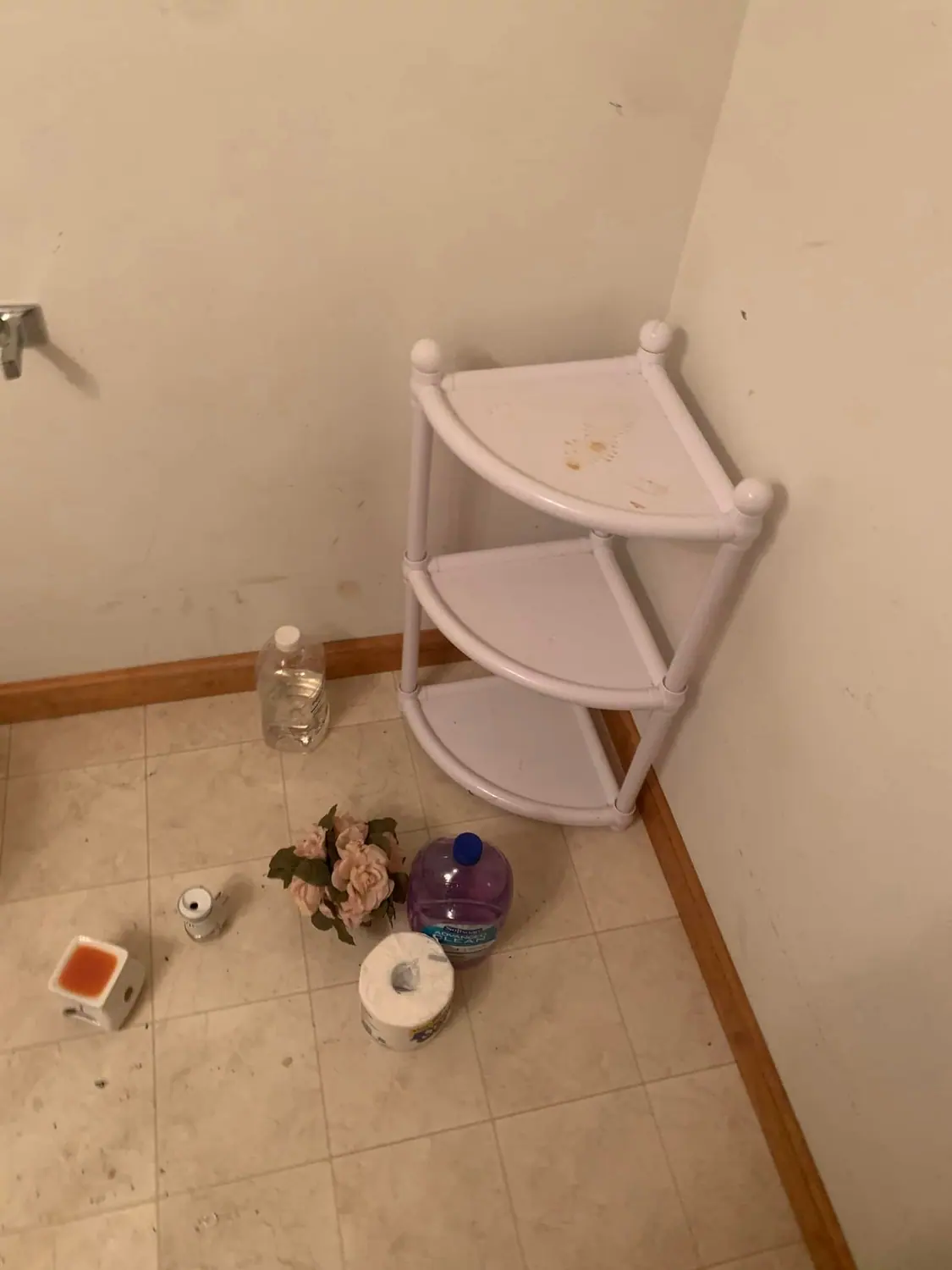 Toiletries and debris on a bathroom floor before cleaning