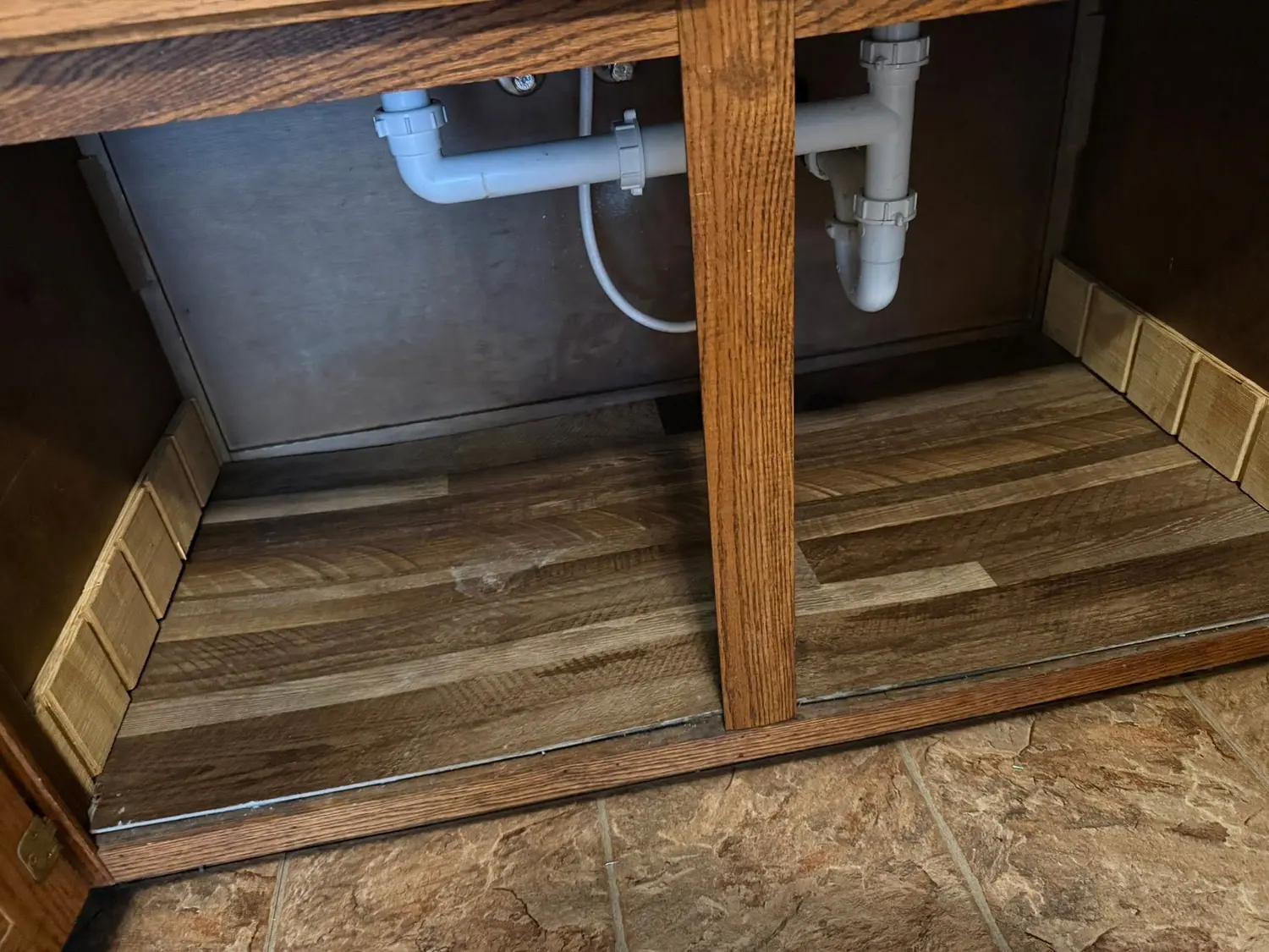 Grime under a kitchen sink cabinet before a deep clean