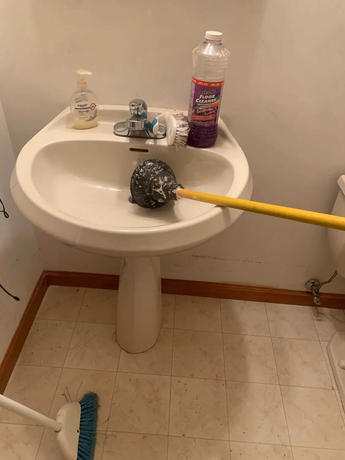 Toilet brush and sink mid-clean during a bathroom deep clean