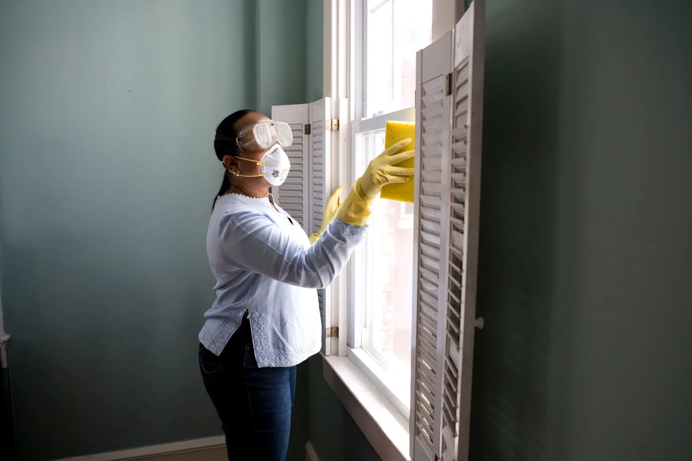 Professional cleaner wiping shutters during a residential visit