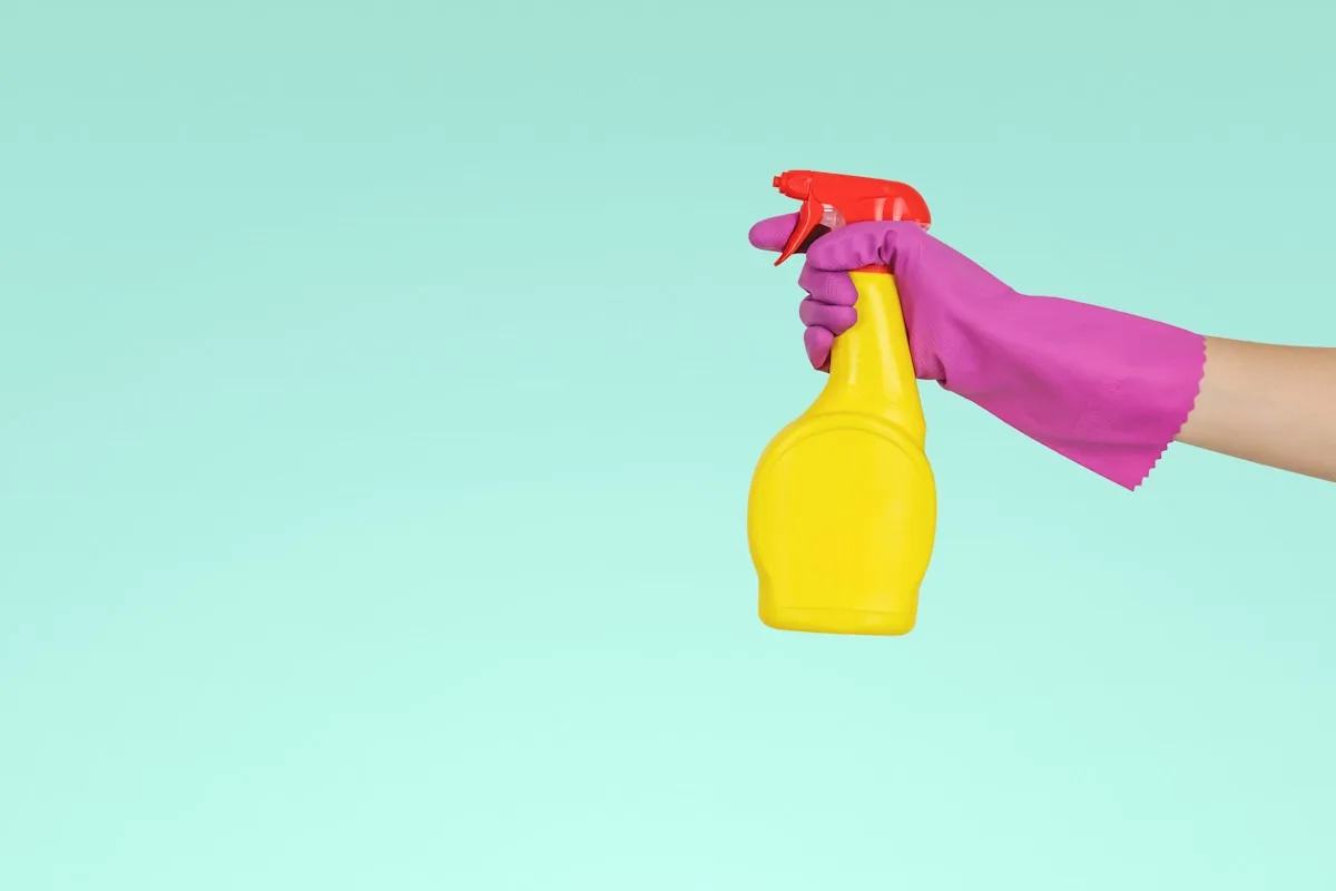 Gloved hand holding a spray bottle of cleaner